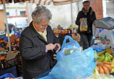 Una anziana paga la frutta acquistata in un mercato a Pisa in una foto d'archivio.