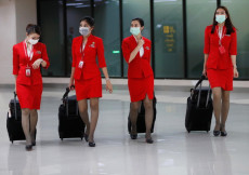 Assistenti di volo cinesi indossano mascherine all'ingresso di un aeroporto.