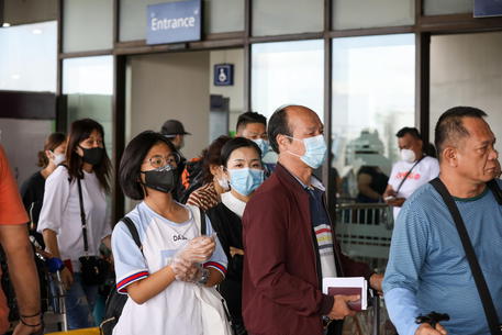 Cittadini cinesi con le mascherine in attesa di entrare all'aeroporto Ninoy Aquino in Manila, Filippine