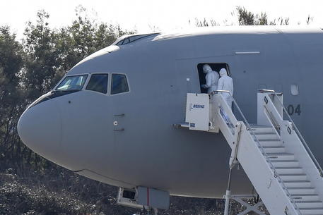 Persone con equipaggiamento protettivo entrano al Boeing KC-767A dell'aviazione militare italiana con a bordo 57 passegeri Italiani arrivati da Wuhan alla base militare Mario De Bernardi a Pratica di Mare, al sud di Roma.