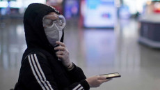 Un ragazzo con mascherina e occhialoni per difendersi dal coronavirus e smartphone in mano.