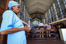 Una donna con una bottiglia di disinfettante all'ingresso della Basilica Cattolica di Nairobi.
