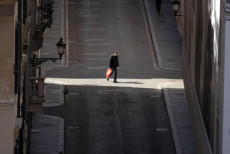 Un uomo cammina nella via Condotti deserta di Milano.