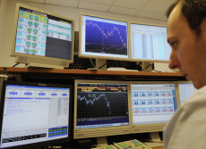 Un operatore finanziario osserva l'andamento della Borsa in una sala operativa di Milano.