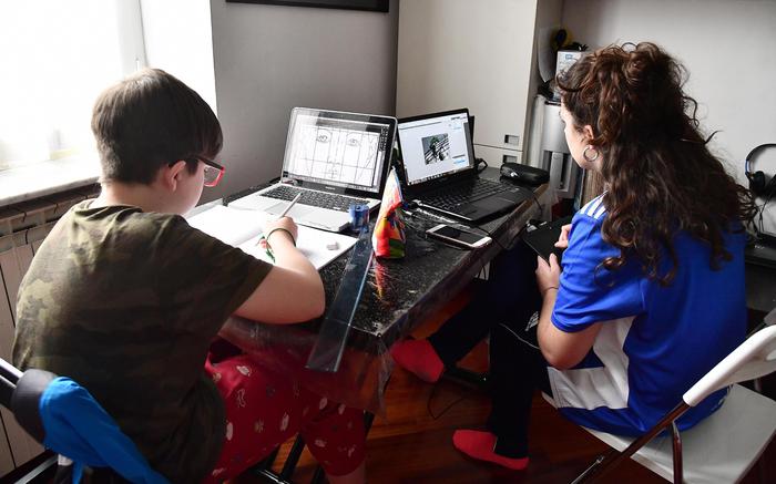 Due studenti seguono le lezioni online da casa.