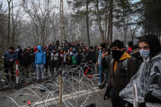 Un gruppo di migranti aspetta il passo della pattuglia della polizia anti-sommosse nel confine della Grecia con la Turchia, in Pazarkule, nella provincia turca di Edirne.