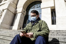 Un signore con mascherina per proteggersi dal Coronavirus in piazza affari davanti all'ingresso della Borsa a Milano, 24 gennaio 2020.