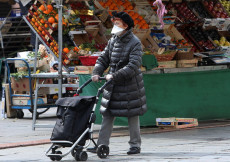 Una donna con la mascherina fa la spesa al mercato.