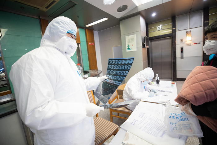 Personale medicoi esamina yn paziente in quarantena in un hotel di Wuhan, Cina.