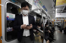 Passeggeri con mascherine salgono sulla metropolitana a Tokyo.