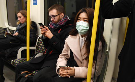 Persone con la mascherina alla metropolitana di Londra.