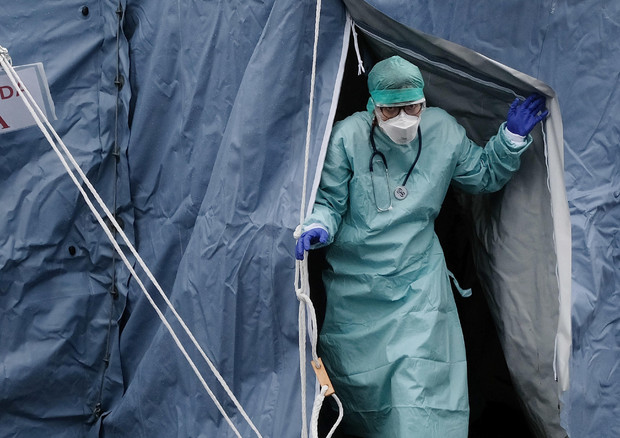 Un infermiere con tuta e mascherina escer da una tenda al check point sanitario accanto al Pronto Soccorso degli Spedali civil per il coronavirus, Brescia.
