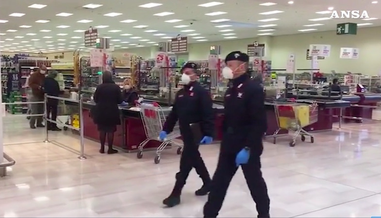 Carabinieri in divisa con mascherine in funzione di controllo in un supermercato.