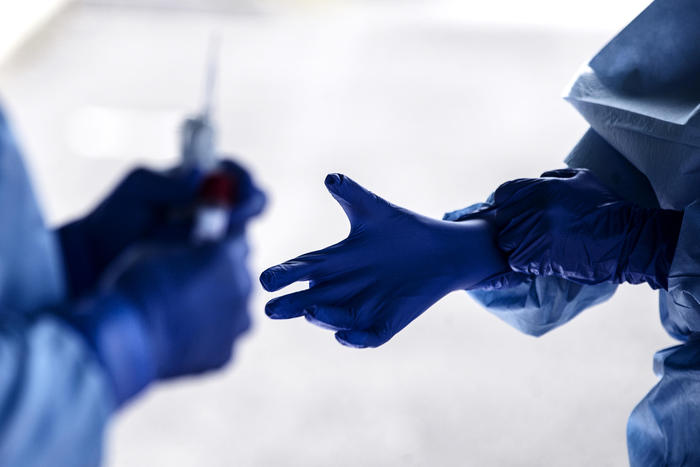 Mani di due dottori che si scambiano un tampone per il controllo del Coronavirus..
