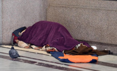 Un senzatetto dorme in un sacco a pelo sotto i portici delle vie centrali di Torino, 17 marzo 2020.