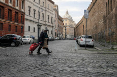 Un senzatetto cammina solitario in Borgo Sant'Angelo, vicino alla Basilica di San Pietro.