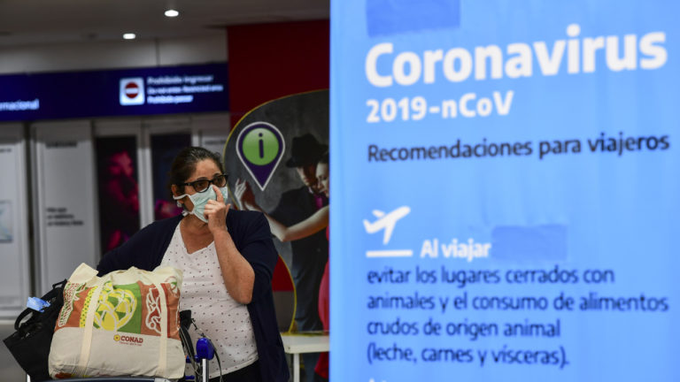 Una passeggera con mascherina esce dall'aeroporto di Buenos Aires.