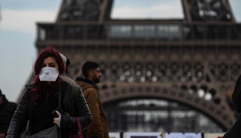 Un turista con mascherina passaggia davanti alla Torre Eiffel a Parigi.
