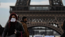 Un cittadino con mascherina visita la Torre Eiffel a Parigi.