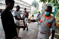 Personale di servizio versa gel sanitario nelle mani di passanti a Lagos, Nigeria.