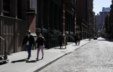 Persone con mascherine camminano a New York mantenendo la distanza sociale.