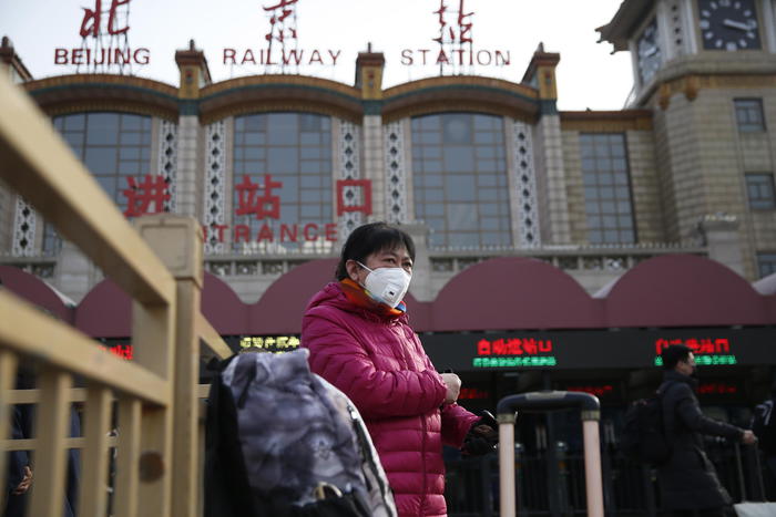 Un passeggero con mascherina alla stazione ferroviaria di Pechino.
