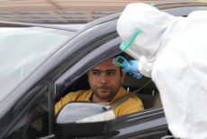 Un lavoratore sanitario misura la febbre ad un automobilista in un controllo stradale ad Ankara.