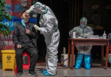 Personale medico on tute protettive realizzano test per corovairus ad un uomo in una strada di Wuhan, Cina