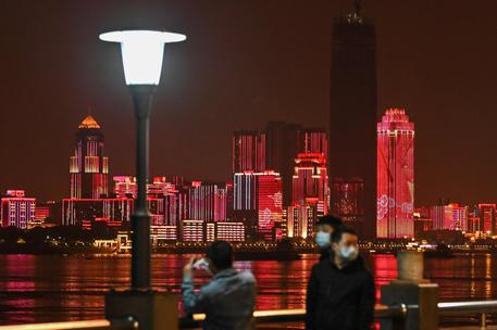 Persone con mascherine passeggiano lungo la riva del fiume Yangtze nella cittá di Wuhan,Cina.