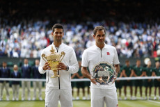 Il serbo Novak Djokovic (S) con il trofeo del campionato dopo aver battuto allo svizzero Roger Federer (D) alla finale di Wimbledon al England Lawn Tennis Club,di Londra,