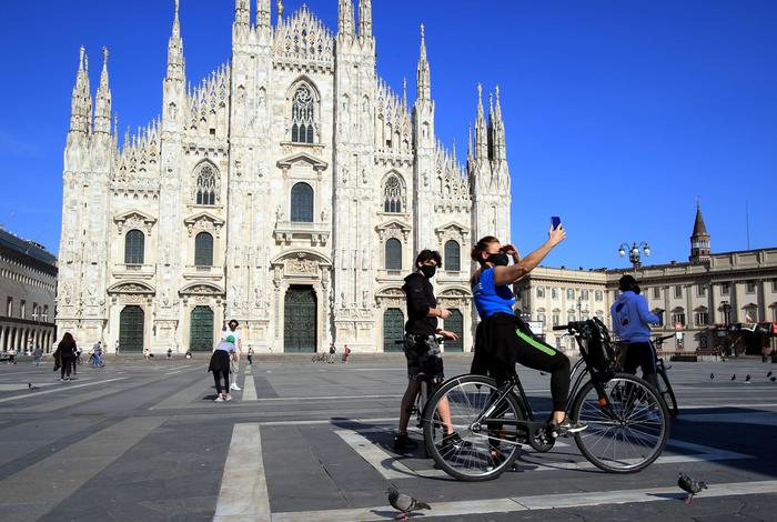 Persone passeggiano o vanno al lavoro in piazza Duomo e in Galleria Vittorio Emanuele in un primo, piccolo ritorno alla vita normale, Milano