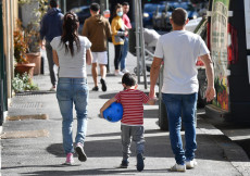 Genitori e bambini a passeggio in una strada di Genova alla riapertura
