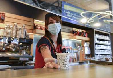 Una lavoratrice con mascherina in un bar di Milano.