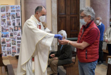 Il celebrante don Carlo Seno si igienica le mani e distribuisce l' eucarestia nella chiesa dei Santi Gervaso e Protaso a Gorgonzola