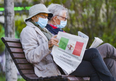 Coppia di anziani seduti al parco leggendo il giornale a Milano.