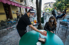 Un cameriere serve da bare con la mascherina e la visiera in un locale del quartiere del Quadrilatero a Torino