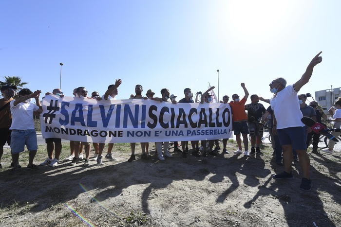 Un gruppo di contestatori mostrano uno striscione 'Salvini Sciacallo' nella zona rossa di Mondragone (Caserta) dove il leader della Lega Matteo Salvini è atteso per un incontro con la cittadinanza
