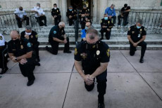 Un gruppo di polizziotti s'inginocchia in segnale di appoggio ai manifestanti, durante un rally a Coral Gables, Florida .
