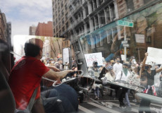 Un automobilista vede passare una manifestazione di protesta a New York.