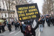 Una manifestante porta un cartellone con la scritta: Giustizia per Theo e Adama, Zyed e Bouna. noi non scordiamo" durante una protesta contra la violenza della polizia a Parigi.