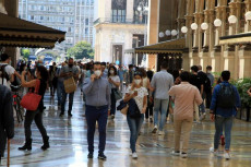 Offerte e saldi per invogliare le spese con diverse code fuori dai negozi di abbigliamento di Milano
