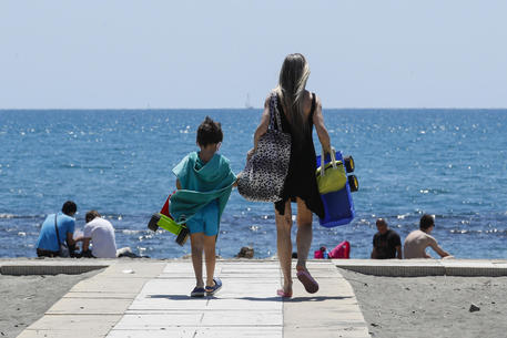 Mamma con bambino in mano sulla pedana verso la spiaggia di Ostia.