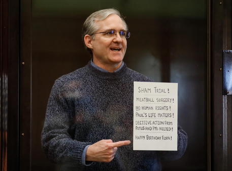 L'ex marine Paul Whelan sostiene un foglio con la scritta : "processo farsa" nel tribunale di Mosca.