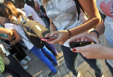 Adolescenti guardando lo schermo del proprio cellulare.