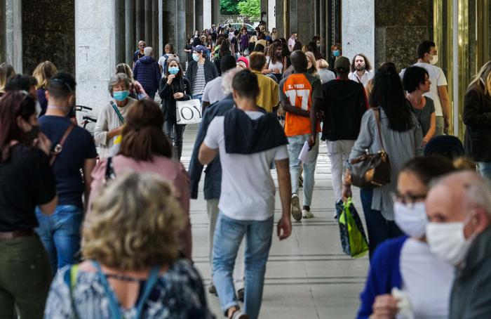 Persone passeggiano e discutono sotto i portici di via Roma, Torino