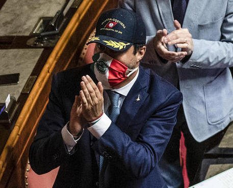 Matteo Salvini al Senato con berrettino della Guardia Costiera applaude ironico.
