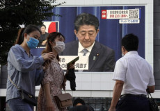Immagine del premier giapponese Shinzo Abe in uno schermo gigante nella via pubblica mentre da le dimissioni in diretta televisiva.