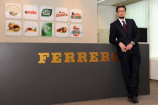 L'imprenditore Giovanni Ferrero davanti al logo della sua marca.