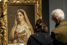 Due persone davanti al quadro di Raffaello 'Ritratto di donna detta la velata'.