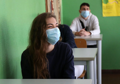 Alcuni studenti con la mascherina seduti ai banchi di scuola.
